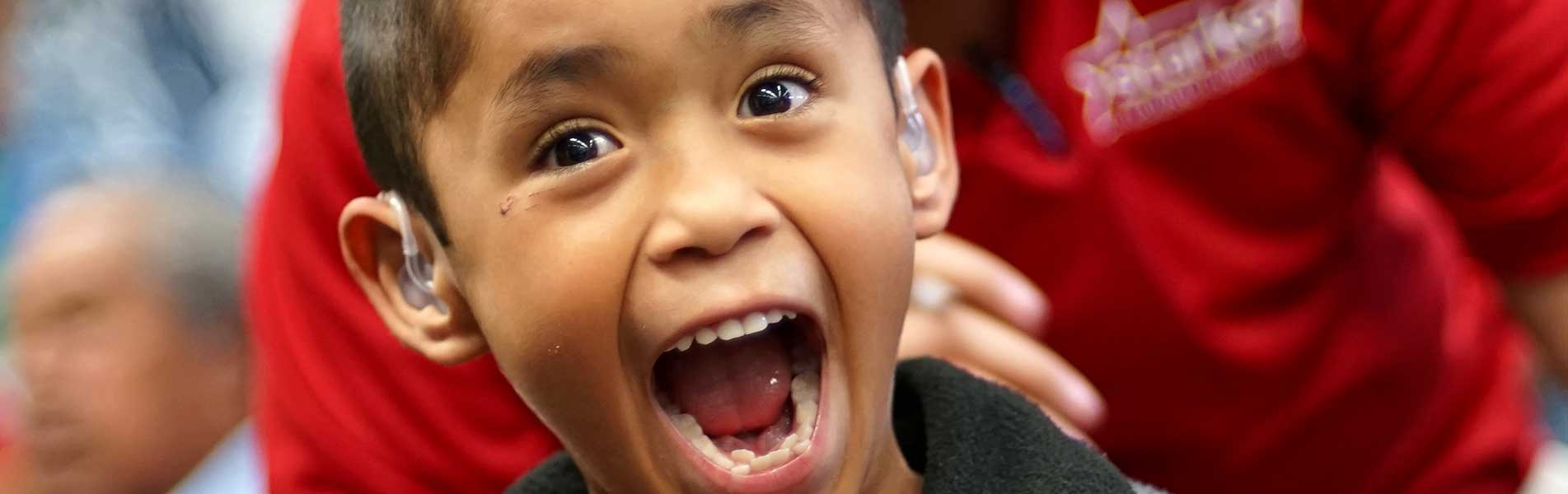 a boy very excited that he can hear with his new hearing aids