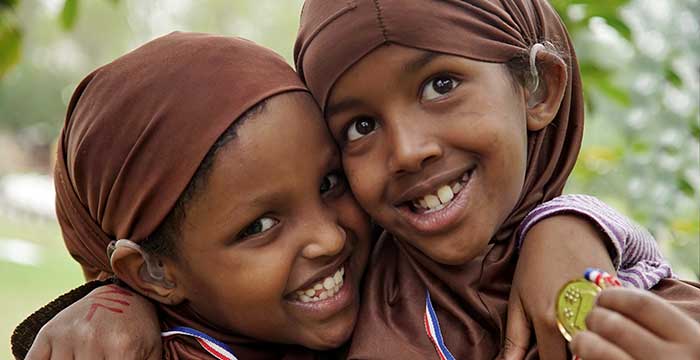 two girls in Nairobi hugging and happy with their hearing aids