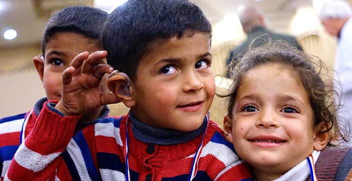 Three kids excited that one boy has hearing aids now