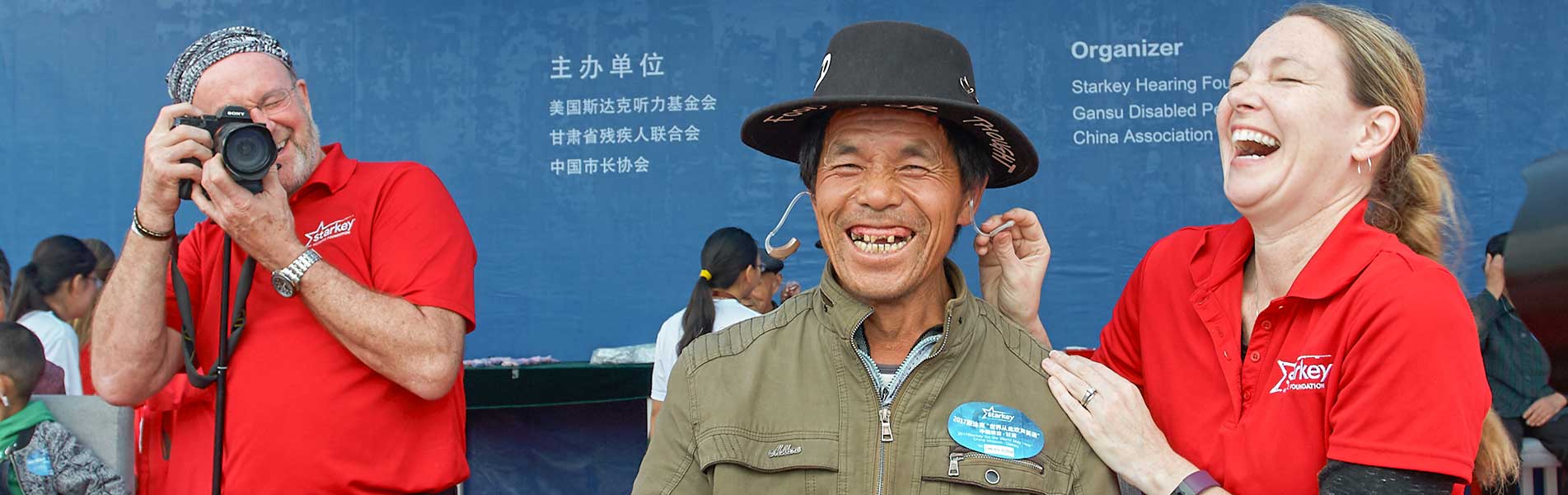 Starkey staff applying hearing aid to an older man in China