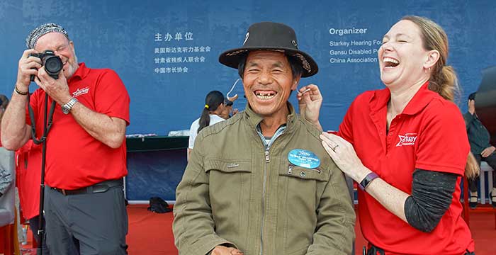 Starkey staff applying hearing aid to an older man in China